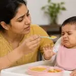 Indian mother 11 महीने के बच्चे को spoon से खाना खिलाने की कोशिश कर रही है लेकिन बच्चा खाना खाने से मना कर रहा है
